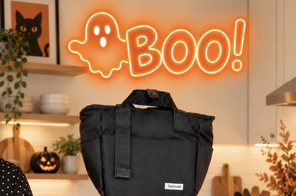 Spixal black Commute lunch tote on a coral silicone bento and black lunch box under a BOO! neon sign