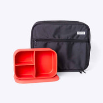 Black zippered lunch bag and orange silicone bento box on a white background