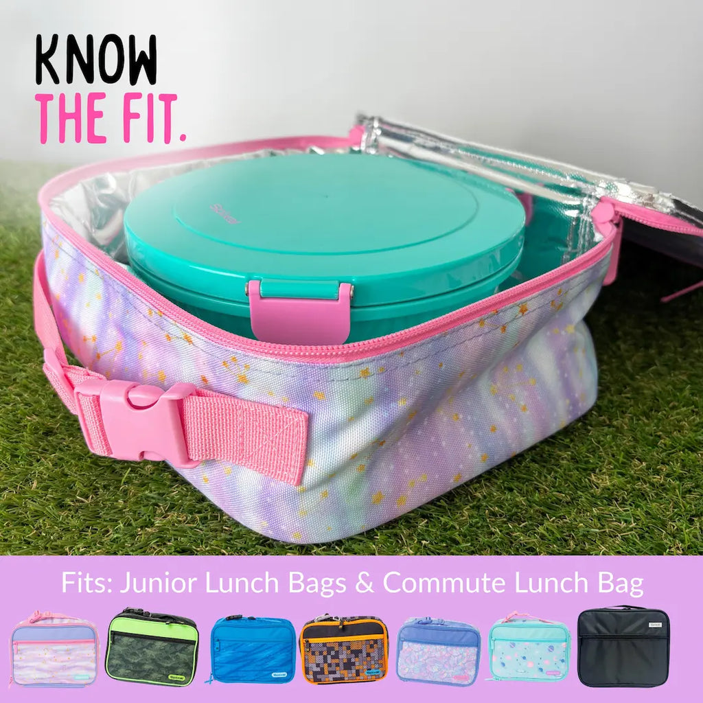 A unicorn stars lunch bag with pink trim and a buckle strap, shown open with a teal roundie inside. The bag is placed on grass, with the text 'KNOW THE FIT.